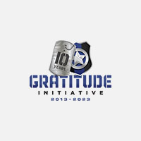 Logo of Gratitude Initiative with a dog tag and shield design, marked "10 Years," showcasing the concept from 2013-2023 on the homepage.