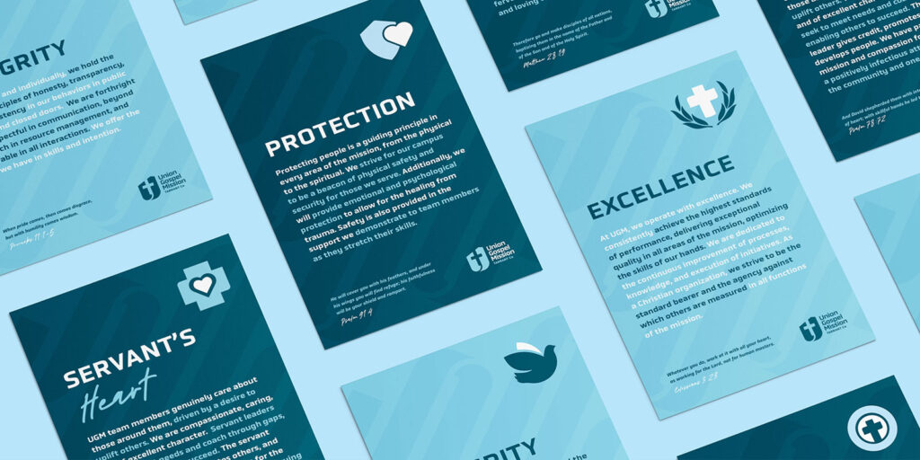 A flat lay of blue posters featuring text and icons about values such as protection, excellence, integrity, and servant’s heart, arranged on a light blue background.