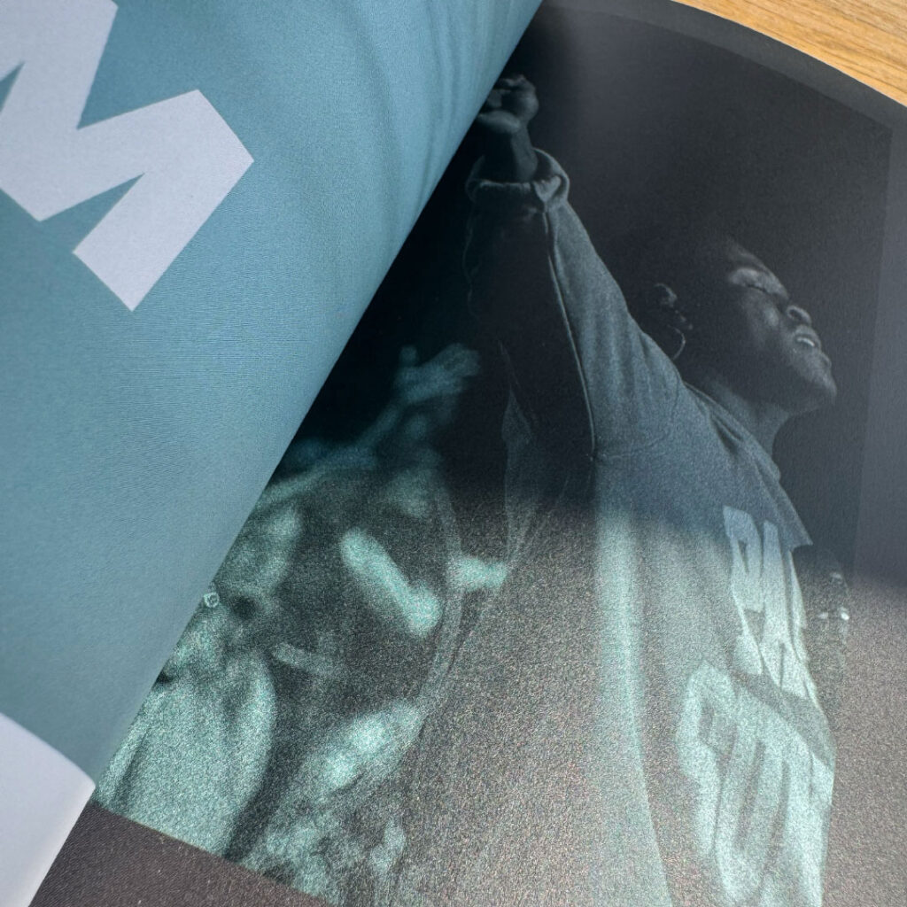 Close-up of an open magazine featuring a grainy black-and-white photo of a person raising their arm, partially covered by the page above—an example of striking print design in a Goff Companies case study.